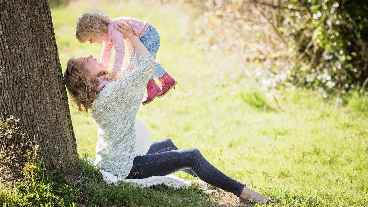 Woman holding a child under a tree in a park